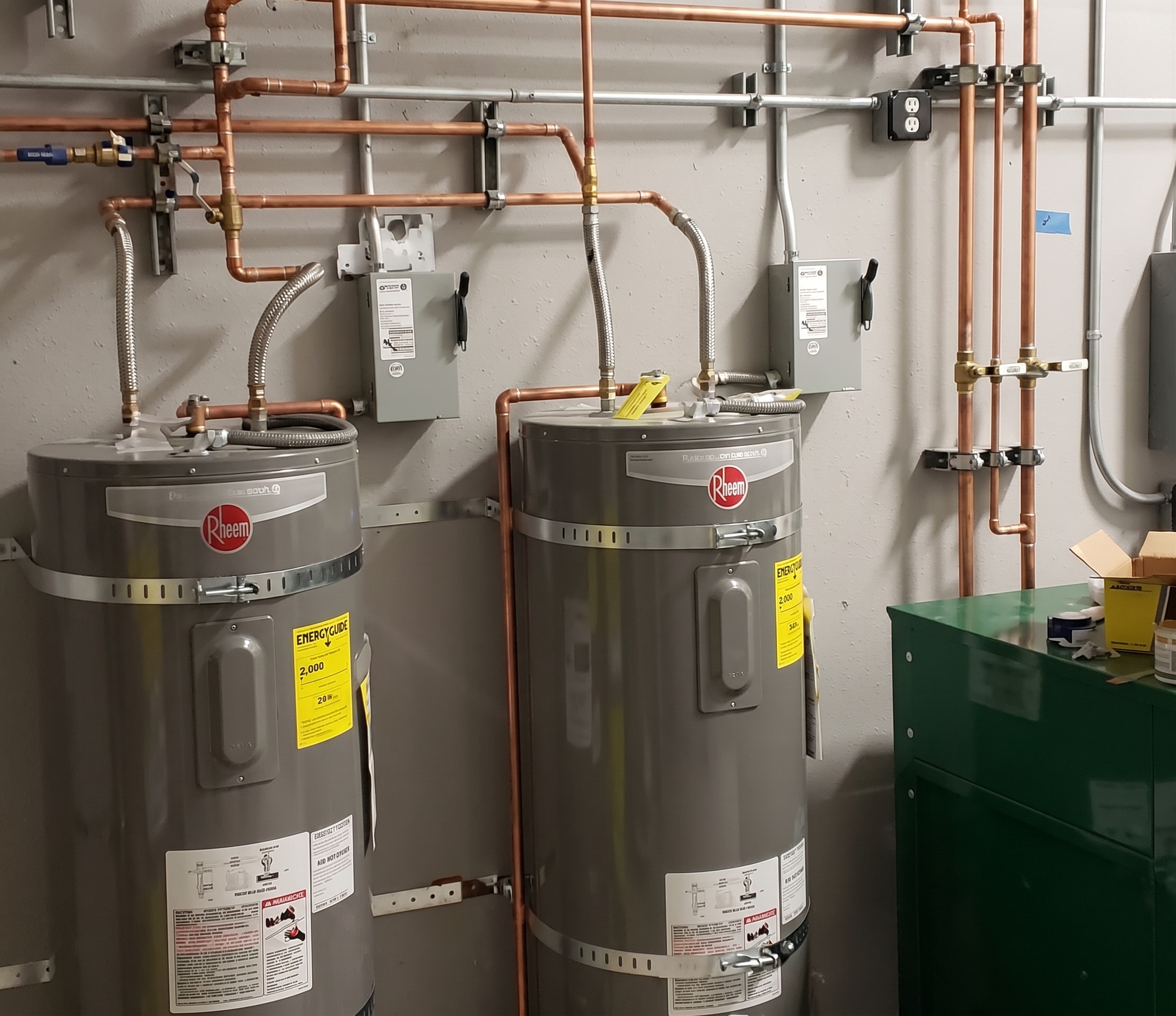 Two Rheem water heaters with copper piping installed in a utility room