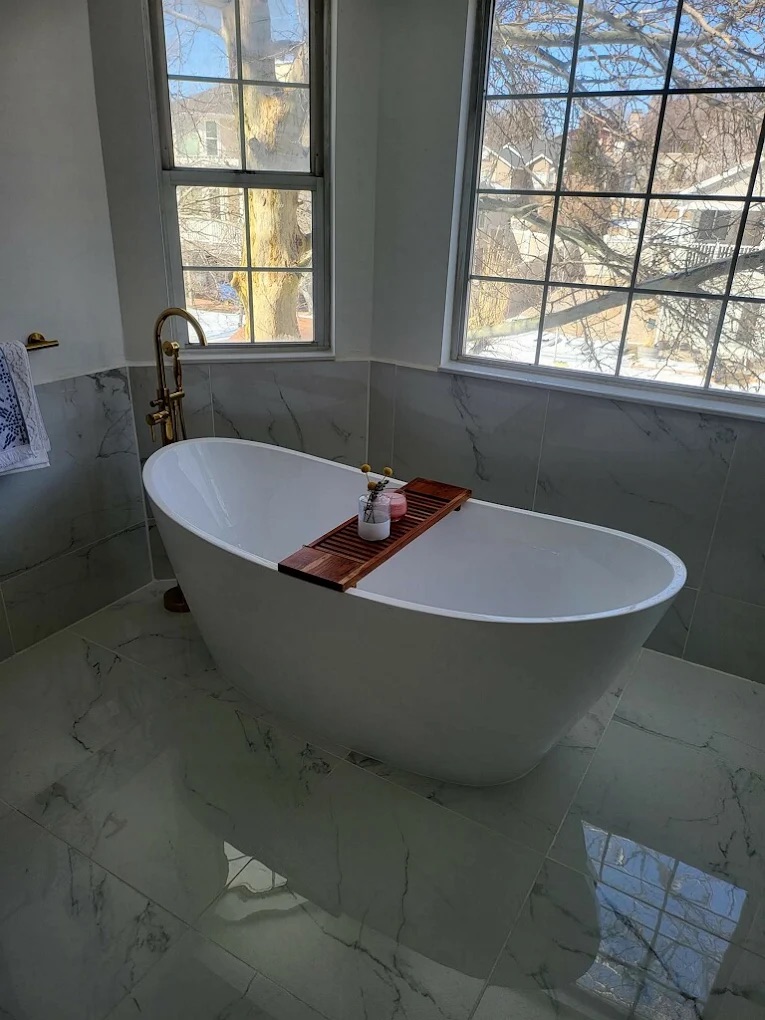 Freestanding bathtub with marble tile and brass floor faucet