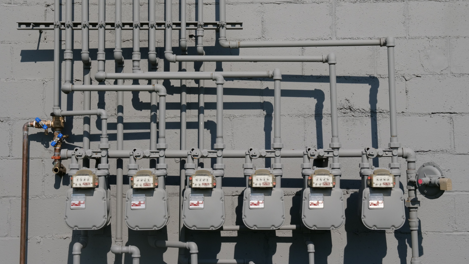 Row of natural gas meters and piping mounted on an exterior wall