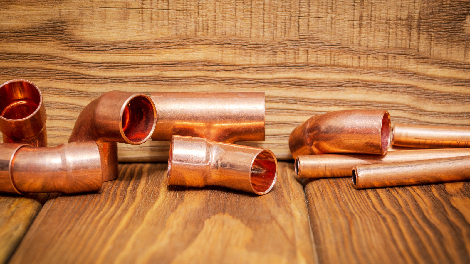Copper plumbing pipes and fittings arranged on a wooden workbench