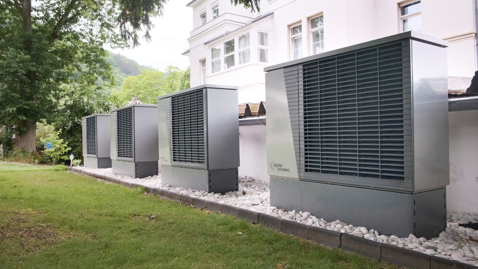 Four modern outdoor climate units installed in a row beside a white building