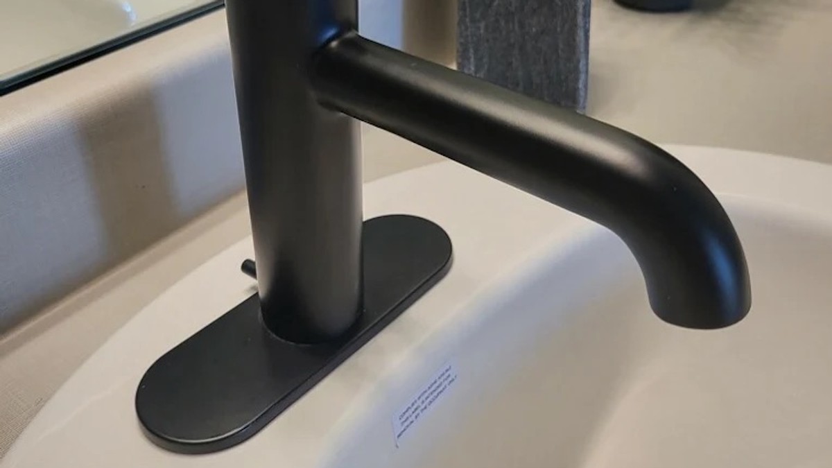 Matte black faucet spout tipping into a white bathroom sink